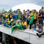 Para pengunjuk rasa, pendukung mantan presiden Brazil Jair Bolsonaro, berdiri di atap gedung Kongres Nasional setelah mereka menyerbunya, di Brasilia, Brazil, Minggu, 8 Januari 2023. (Foto: AP/Eraldo Peres)